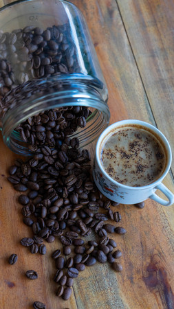 White coffee cups and coffee beans that spill around with wooden table backgroundsの写真素材