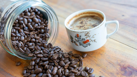 White coffee cups and coffee beans that spill around with wooden table backgroundsの写真素材