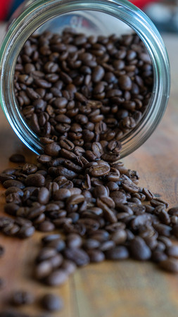 coffee beans spilled against a wooden table backgroundの写真素材