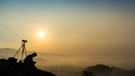 sunrise views in the summer that emerge from the hills in a village with photographer sillhouetteの写真素材