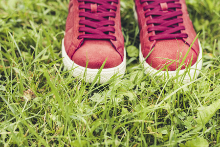 Pair of sport shoes of pink suede on the grass in parkの写真素材