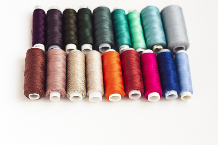 Colored sewing thread coils on white background with copy space for text