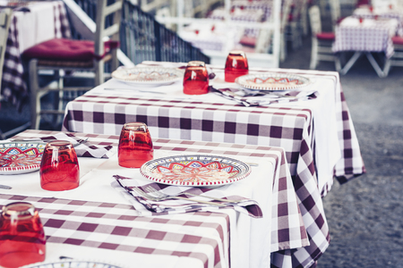 Serving on the table in the restaurant in Catania, Sicily, Italy: plates, glasses and napkinsの写真素材