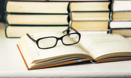 Books background, open book and glasses on white wooden table in office business background for...