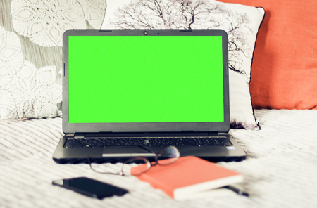 Green screen laptop, notebook, smartphone, glasses and pen on bad, education concept background.の写真素材
