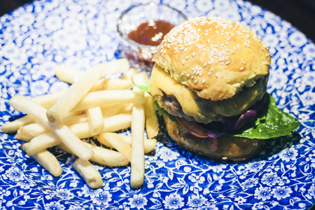 Chicken hamburger, fries and sauce on the blue plate in restaurantの写真素材