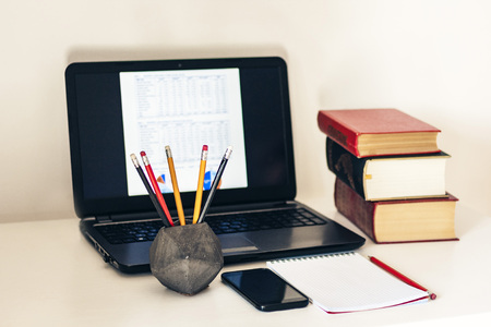 laptop, stack of books, notebook, smartphone in office background for education learning conceptの写真素材