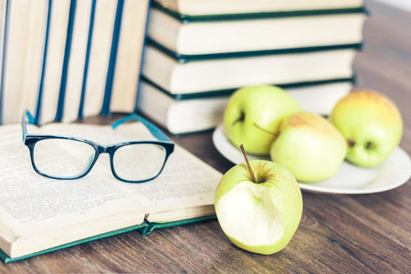 Stack of books, open book, glasses and green apples, background for education learning conceptの写真素材