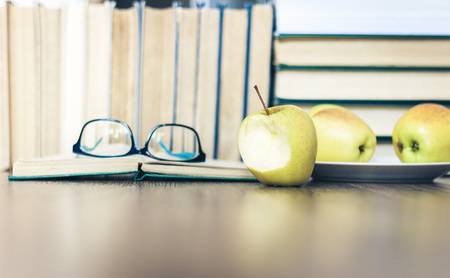 Stack of books, open book, glasses and green apples, background for education learning conceptの写真素材