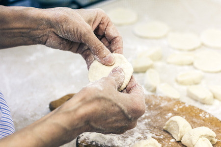 Dumplings. Dough with cabbage filling on the cook's handsの写真素材