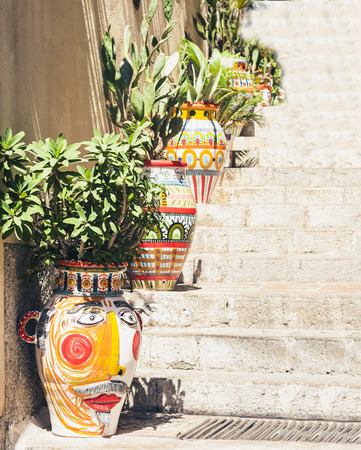 Plant in clay pot on the historic street of Taormina, Sicily, Italy, traditional architectureの写真素材