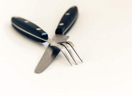 Close up knife and fork crossed, isolated on white backgroundの写真素材