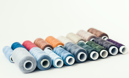 Colored sewing thread coils on white background with copy space for text