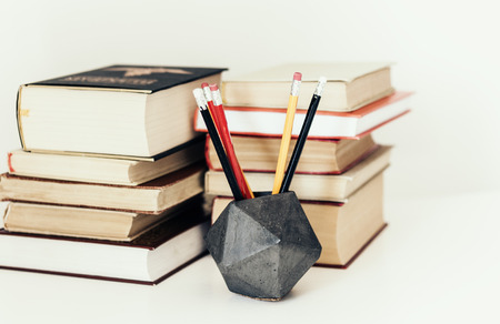 Stack of book education concept background, many books piles and pencils in concrete holder on white table with copy space for textの写真素材