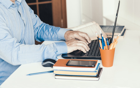 Close-up of hand man using a mouse and typing on laptop on white table, business concept