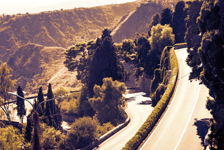 Sicily sunset with curvy serpentine road in green mountains - beautiful panorama of Taorminaの写真素材