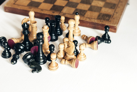 Old well used wooden chess pieces on a chessboard, retro leadership concept on white background