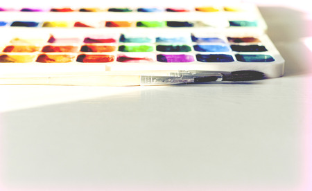 Watercolor paint and brushes well used on white wooden table with copy space for text