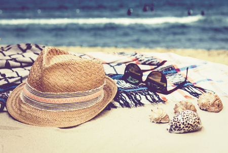 Straw hat, sun glasses and cover-up beachwear wrap on a tropical beach  with sea shellsの写真素材