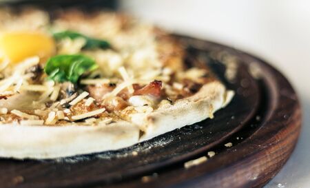 pizza with ham, mozzarella, tomato sauce from the oven on wooden plate in restaurant of Catania, Sicily, Italyの写真素材