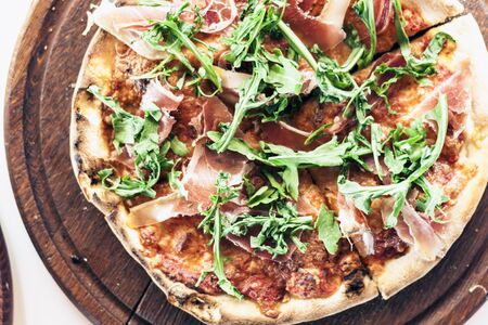 pizza with ham, mozzarella, tomato sauce from the oven on wooden plate in restaurant of Catania,...