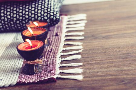 Cozy home interior decor background, burning candles in coconut shell on a multi-colored rugの写真素材