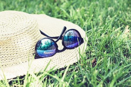 female wicker hat and sunglasses on the lawn on the grass in the parkの写真素材