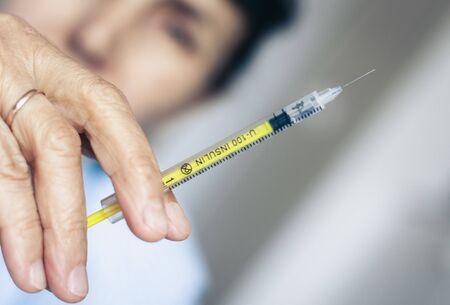 Pile of medical syringes for insulin for diabetes in woman handの写真素材