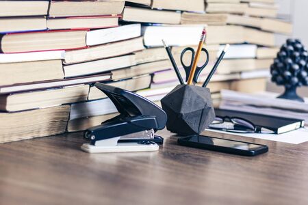Stack of old book on wooden table, notebook, smartphone, stationery and paperweight. Education writer concept backgroundの写真素材