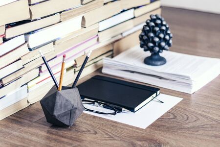 Stack of old book on wooden table, notebook, smartphone, stationery and paperweight. Education writer concept backgroundの写真素材