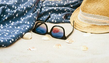 Vintage summer wicker straw beach hat, sun glasses, cover-up beachwear wrap on the sand, tropical...
