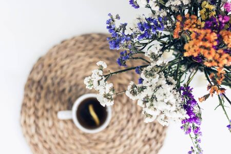bouquet of flowers, lemon tea in a white ceramic cup on a straw wicker stand on the table, top viewの写真素材