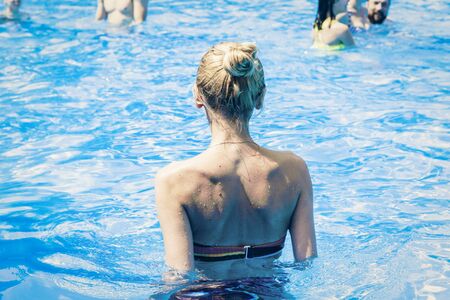 the girl the blonde stands in the swimming pool with her back, tropical concept background