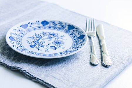 Table setting for dinner: a white plate, a fork, a knife on a woven cloth napkin with an embroidered pattern,  traditional handmade in Ukraineの写真素材