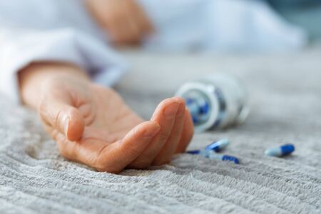 Womanâ€™s hand close up committing suicide by overdosing on medication, pills and bottle...