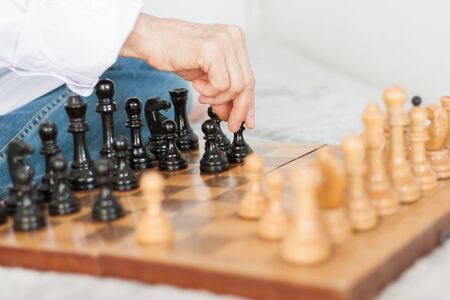 Strategy concept, hand of woman moving wooden chess figure in play, management or leadership...