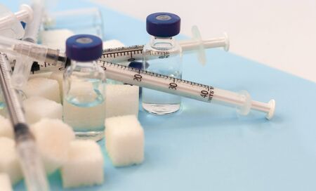 Sugar addiction, insulin resistance, unhealthy diet, sugar cubes, bottles of insulin and syringe for...