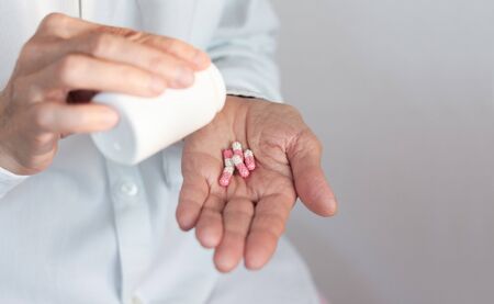 Female hand close up holding a medicine, elderly woman hands with pill on spilling pills out of...