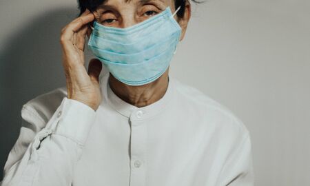 Coronavirus quarantine and Air pollution pm2.5 concept. Sick sad depressed, thoughtful old woman wearing respirator mask for protect.の写真素材