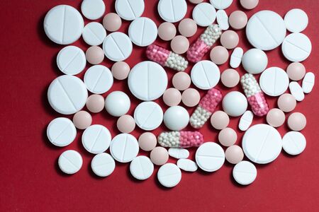 Heap of white pills, tablets, capsules on red background. Drug prescription for treatment medication health care concept wth copy spaceの写真素材