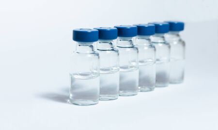 Glass medicine bottles with injection fluid with blue aluminium caps for vaccination. Coronavirus...