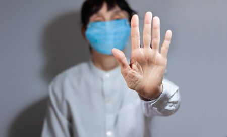 Stop coronavirus quarantine and Air pollution pm2.5 concept. Sick old woman wearing respirator mask for protect with outstretched arm.  epidemic virus symptoms backgroundの写真素材