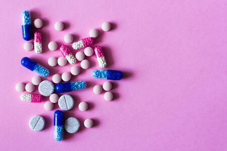 Heap of colorfull pills, tablets, capsules on pink background. Drug prescription for treatment...