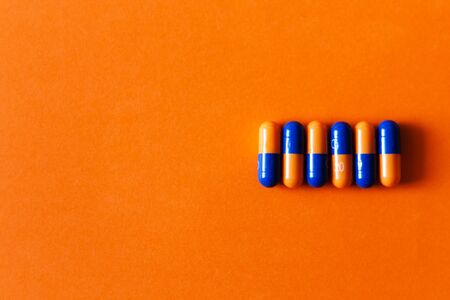 Pills, medicine for pneumonia, antibiotics on an orange backgroundの写真素材