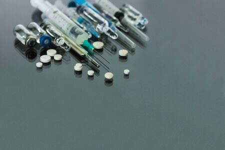 Thermometer, pills, injection vaccine ampoules and syringe for vaccination on glass backgroundの写真素材