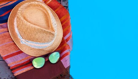 Vintage summer wicker straw beach hat, sun glasses, cover-up beachwear wrap near swimming pool, tropical backgroundの写真素材