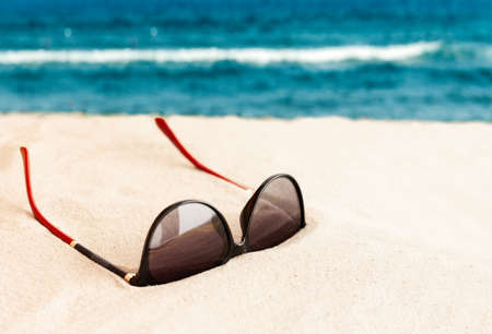 Sunglasses on the seashore, tropical beach vacation background