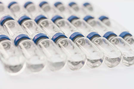Glass medicine bottles with injection fluid with blue aluminum caps and syringe for vaccination. Cancer, painand diabetestreatment, pharmaceutical medicine conceptの写真素材