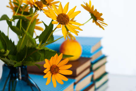Cozy home interior decor: stack of books and vase with yellow flowers on a table. Distance home education.Quarantine concept of stay homeの写真素材