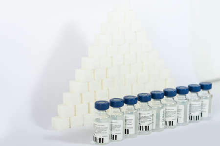 Sugar addiction, insulin resistance, unhealthy diet, sugar cubes pyramid, bottles of insulin and...